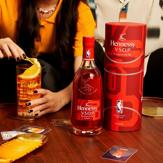 Hennessy V.S.O.P NBA 2024 Limited Edition bottle and packaging, with a cocktail on a wooden table, capturing a courtside collaboration vibe.