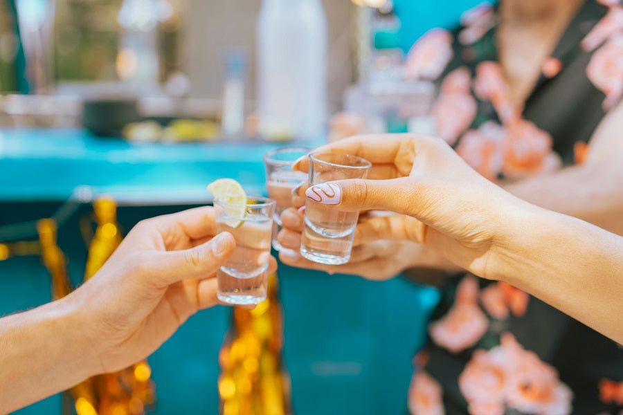 Friends toasting with tequila shots at a tasting party celebration.